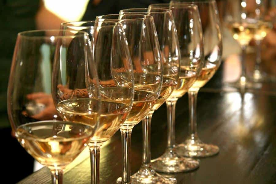 lying glasses of white wine in a row on wooden table at Palivou Estate